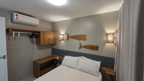 A hotel room with a bed, bedside tables, a wardrobe, wall-mounted lights, and an air conditioning unit. - Sunny Hall By Flat na Praia (Ipojuca)