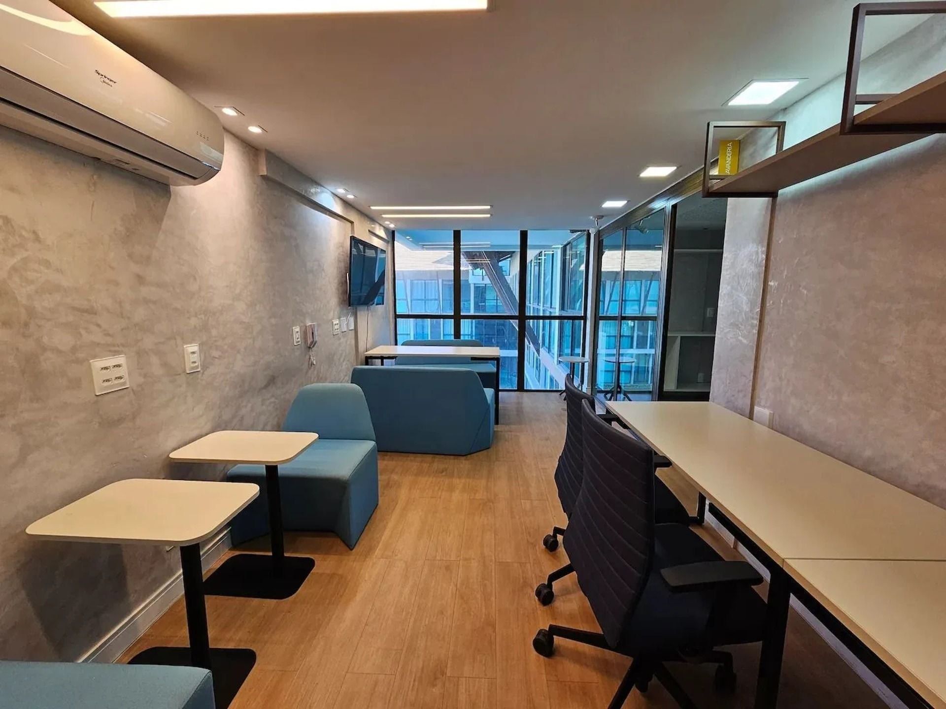 A modern office space with a long table, seating area, and large windows.