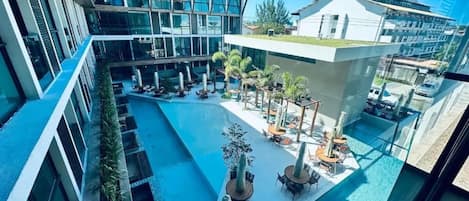 Un edificio moderno con jardín en la azotea, piscina y zonas de estar al aire libre.