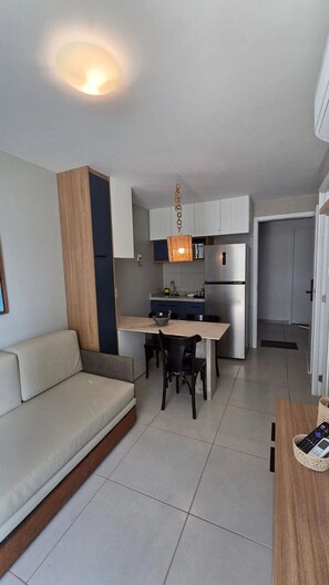 A modern kitchen with a dining area, a sofa, and a small table with a basket. - Sunny Hall By Flat na Praia (Ipojuca)