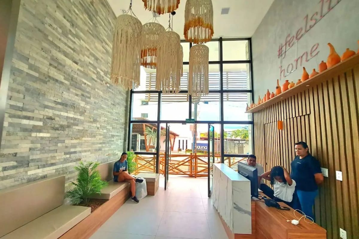 Zona de recepción con diseño moderno, que incluye un mostrador de recepción, un área de estar y lámparas decorativas colgantes.