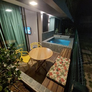 A patio with a wooden table and chairs, a bench, a small pool, and a view of the night sky. - Sunny Hall By Flat na Praia (Ipojuca)
