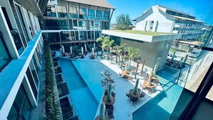 A modern building with a rooftop pool, outdoor seating, and a clear blue sky. - Sunny Hall By Flat na Praia (Ipojuca)