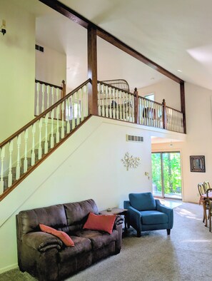 A spacious living area with a high ceiling, a wooden staircase, and a view of the outdoors. - Lovely cottage close to vineyards and beaches. (Benton Harbor)