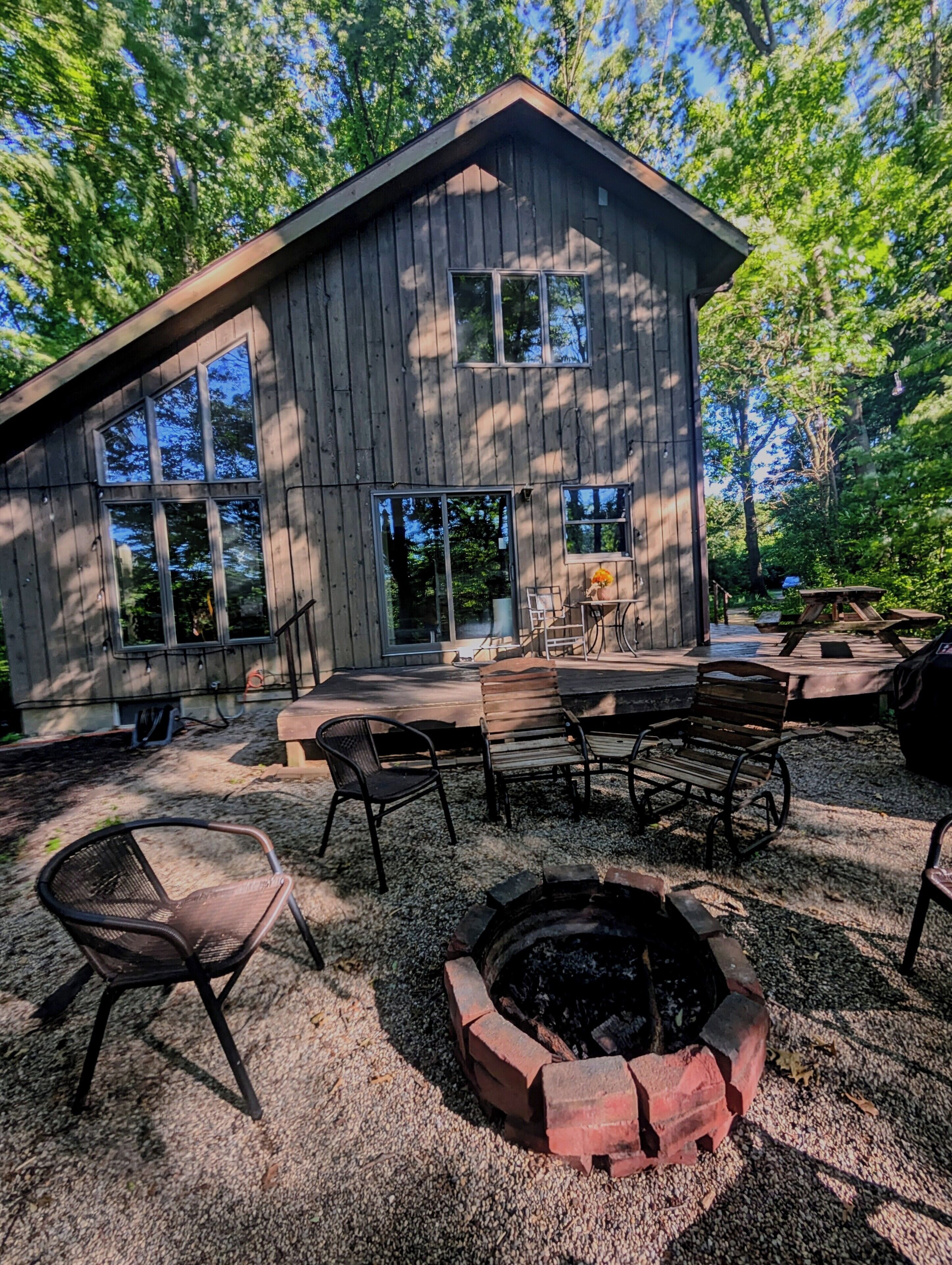 A wooden cabin with a deck, outdoor seating, and a fire pit.