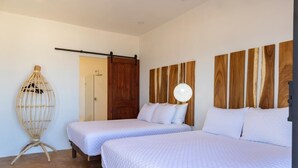 A bedroom with two beds, a wooden headboard, a hanging light fixture, and a door.
