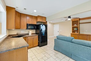 A kitchen with wooden cabinets, a black refrigerator, a microwave, and a sink. - Northshore Lookout: Golf & Beach Retreat (Nags Head)