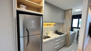 Een moderne keuken met een roestvrijstalen koelkast, een inbouwfornuis en grijze kastjes.