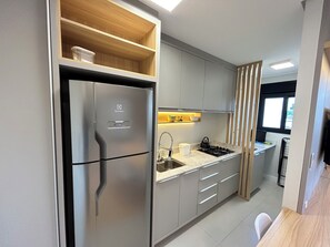 Una cocina moderna con un refrigerador de acero inoxidable, una estufa integrada y gabinetes grises.