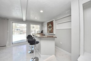 A modern kitchen with a marble countertop, a bar stool, and a decorative stained glass window. - Spacious Pool Home Near IAH Accommodates Families and Groups (houston)