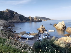 A rocky coastal area with boats docked near the shore, surrounded by natural vegetation and cliffs. - Holiday Home 'Paraiso' with Sea View, Shared Pool and Private Terrace (Costa Paradiso)