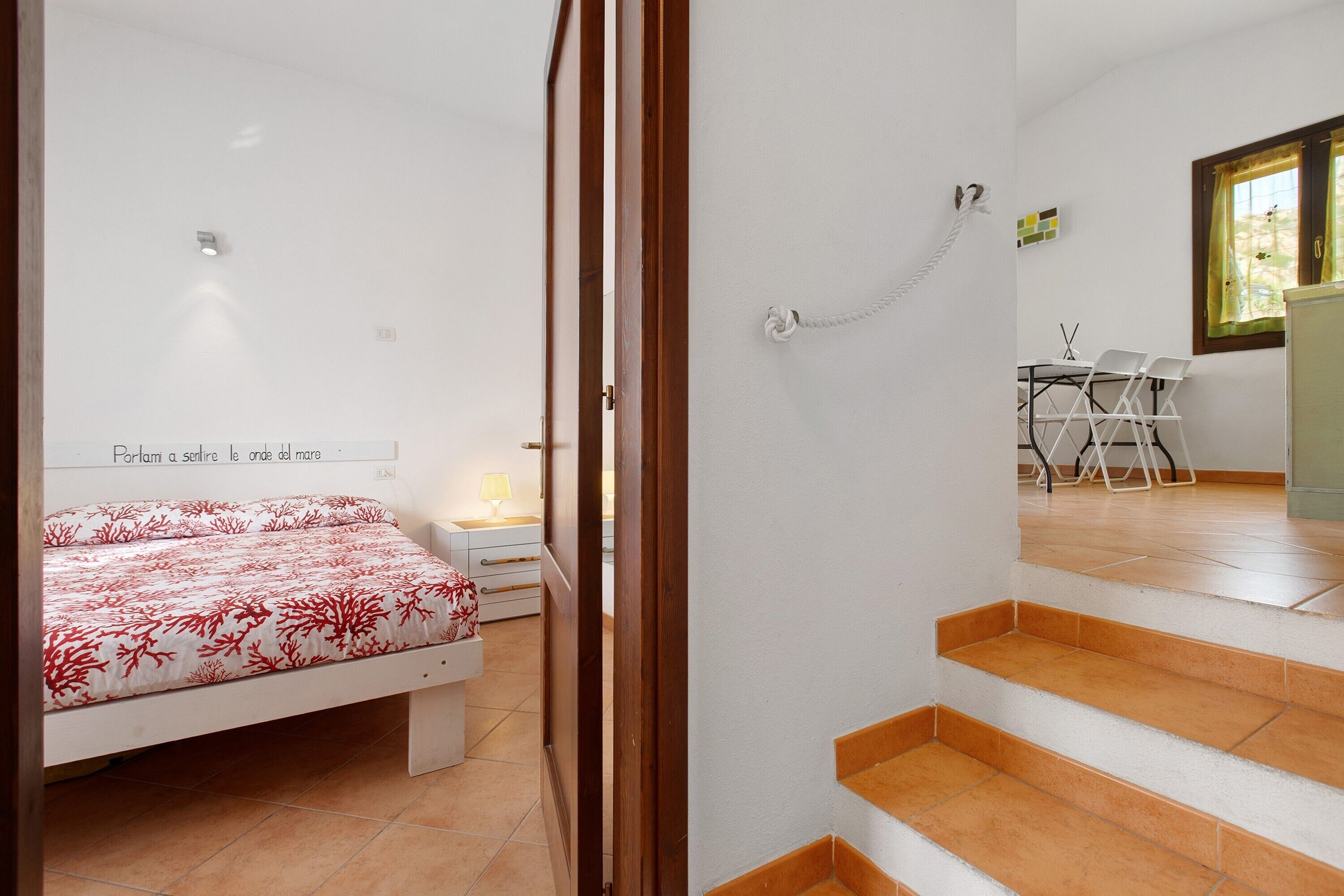 Ein Schlafzimmer mit einem Bett, einem Nachttisch, einem Schreibtisch mit Stühlen und einem Fenster mit Vorhängen.