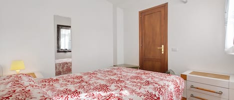 Un dormitorio con cama, mesita de noche, lámpara, armario y puerta.