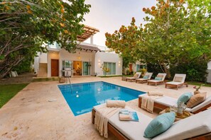 A modern house with a swimming pool, lounge chairs, and a covered patio area. - Luxurious 3 Bedroom Villa With Private Pool in Sosua Ocean Village (Sosúa)