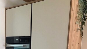 Eine Küche mit Einbauofen und einer Wand in Holzoptik.