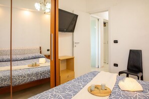 A bedroom with a bed, a TV mounted on the wall, a chair, and a small table with cups. - The Breath of the Sea - Alghero (Alghero)