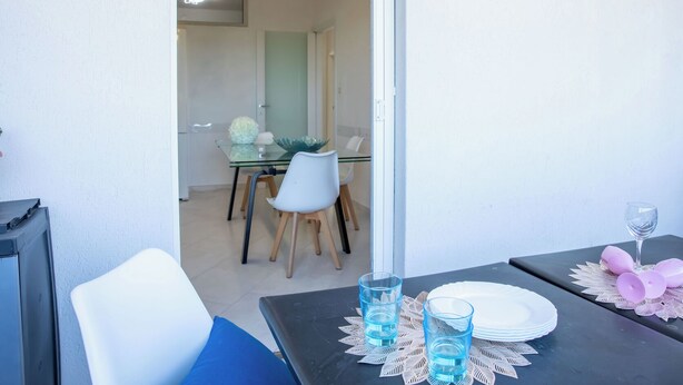 Een eethoek met een tafel voor twee personen, een stoel en een glas water.