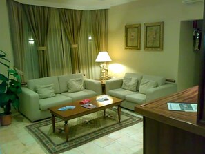 A living room with two sofas, a coffee table, a lamp, and a small table with a newspaper. - Jardim Hotel (Santo Tirso)