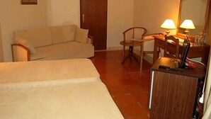 Ein Hotelzimmer mit einem Bett, einem Schreibtisch mit Lampe, einem Sessel und einem Kleiderschrank.