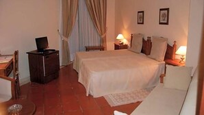 Een hotelkamer met een bed, nachtkastjes, een bureau, een stoel, een televisie en gordijnen.