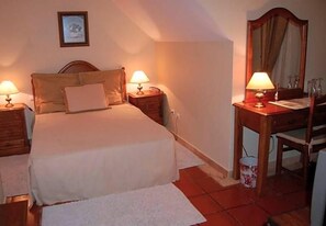 A bedroom with a bed, two bedside tables with lamps, a wooden desk with a chair, and a mirror. - Jardim Hotel (Santo Tirso)