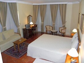 A hotel room with a bed, a sofa, a desk with a television, and a chair. - Jardim Hotel (Santo Tirso)