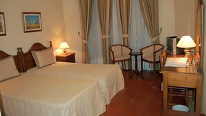 Een hotelkamer met twee bedden, een bureau met lamp, een stoel en een televisie.