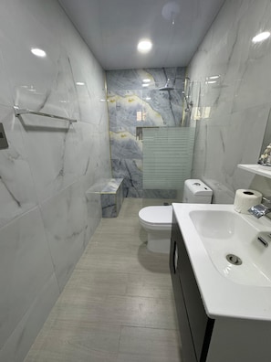 A modern bathroom with a toilet, sink, and shower.