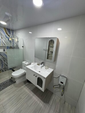 A modern bathroom with a toilet, sink, and shower.