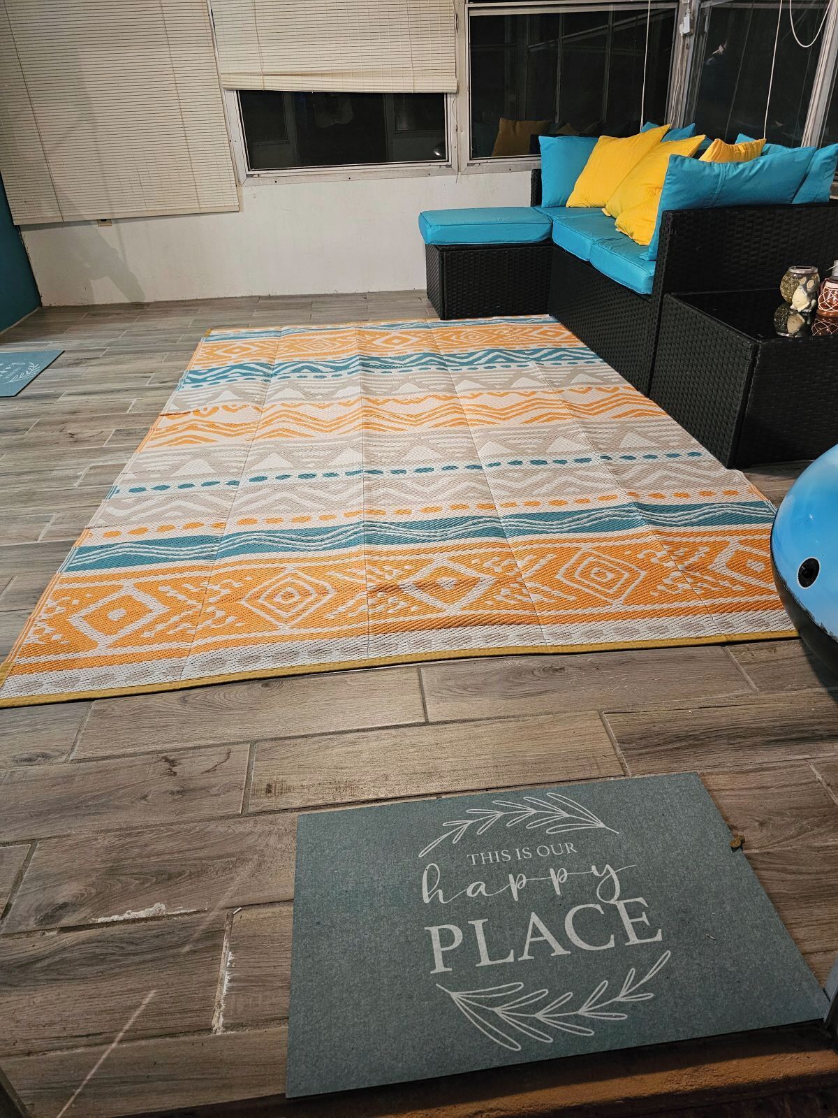 A room with a patterned rug, a blue cushion, and a sign on the floor.