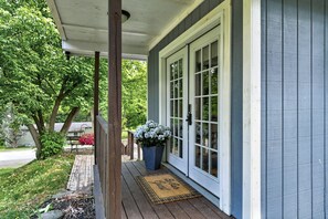 Eine Veranda mit Holzbank, Blumentopf und Fußmatte.