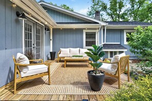Eine überdachte Terrasse mit einer Couch, Stühlen und einem Couchtisch.
