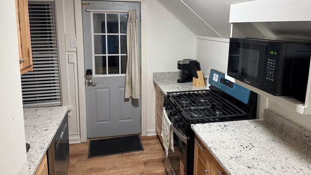 A compact kitchen with a gas stove, a microwave, and a coffee maker. - MedCity Suite—2BR/1BA Near Mayo Clinic (Rochester)