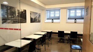 Un salón de conferencias con mesas, sillas y fotografías blanco y negro en las paredes.
