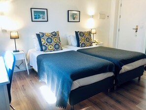 Un lit double avec des coussins à motifs, une table de chevet avec une lampe et un téléphone fixé au mur.
