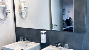 Un baño moderno con dos lavamanos, un espejo grande y un perchero para toallas.