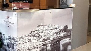 Un mostrador de recepción de hotel con un monitor, un reloj y un adorno en la pared.
