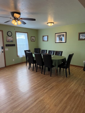 A dining area with a table and chairs, a ceiling fan, and wall-mounted decorations. - Spacious 5-bedroom house ideal for families or fishing groups (Roosevelt)