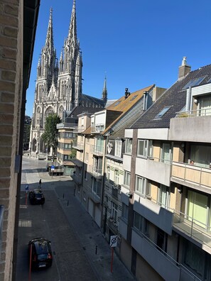 Vista da rua com uma catedral histórica, edifícios modernos e um carro estacionado.
