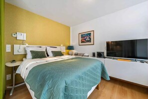 A bedroom with a bed, bedside table, lamp, TV, and artwork on the wall. - 0 bedroom accommodation in OOSTENDE (OOSTENDE)