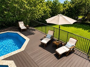 Eine Terrasse mit Pool, Liegestühlen und einem Tisch.