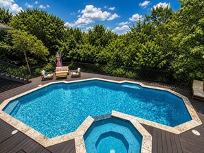 An octagonal swimming pool with a hot tub, surrounded by a wooden deck and a metal fence. - Hill Country Oasis with Pool, Spa & Views (Austin)