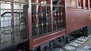 A vintage train carriage with metal bars, wooden panels, and a sign reading 'PROHIBIDO A PASAR.'