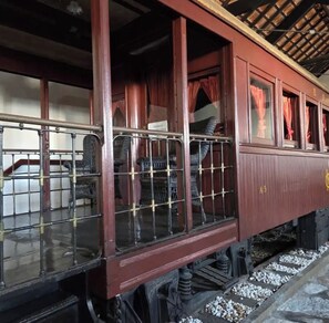 A vintage train carriage with metal bars, wooden panels, and a sign reading 'PROHIBIDO A PASAR.'