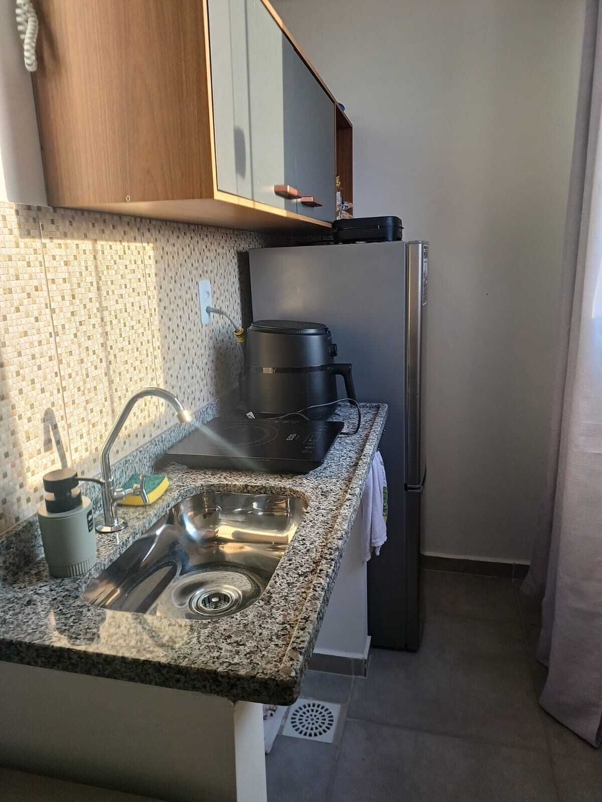 Cocina compacta con encimera de granito, pileta de acero inoxidable, horno integrado y refrigerador.