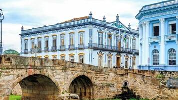 A historic building with classical architecture, a stone bridge, and a flag.