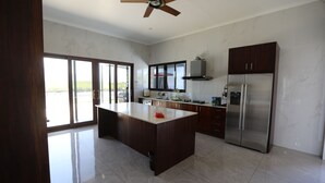 A modern kitchen with a central island, stainless steel appliances, and large windows. - Villa 61 of Naisoso island (Nadi)