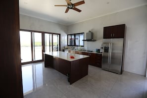 Una cocina moderna con una isla central, electrodomésticos de acero inoxidable y ventanas amplias.