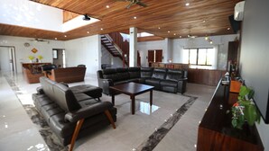 A spacious living area with a wooden ceiling, a black leather sofa, a coffee table, and a staircase leading to another level. - Villa 61 of Naisoso island (Nadi)
