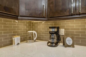 A kitchen with dark wooden cabinets, a coffee maker, a tea maker, and a sign that reads 'Our Little Coffee Bar.' - Wonderful 3-bedroom house in charming Lantana, less than 5 minutes from beach (Lantana)